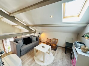 A loft-style living space with a sofa, a small table, wicker chairs, a radiator, and a skylight. - Townhouse - 4/5 guests (Fouras)