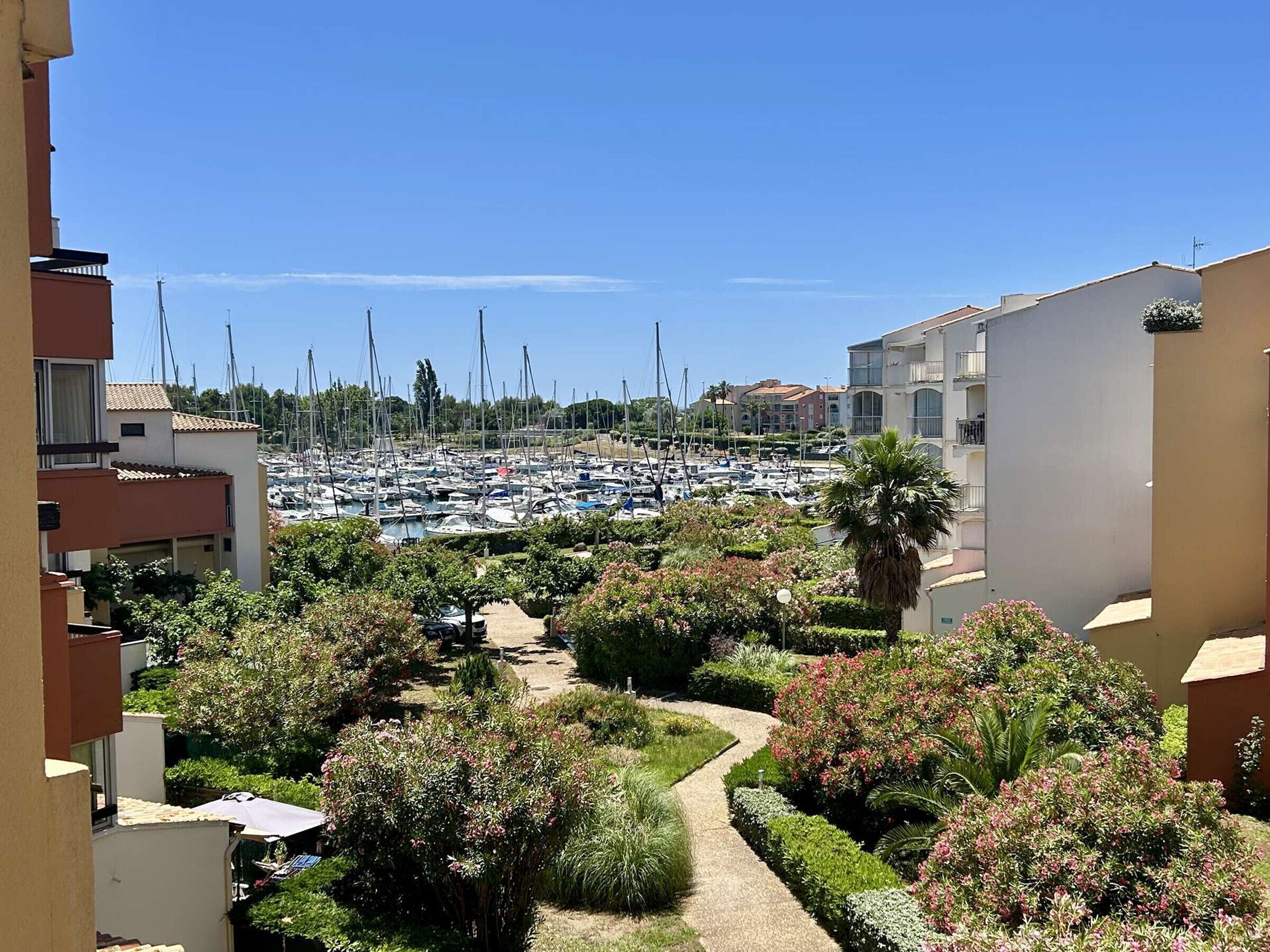 A marina with numerous boats, surrounded by residential buildings and well-maintained gardens.