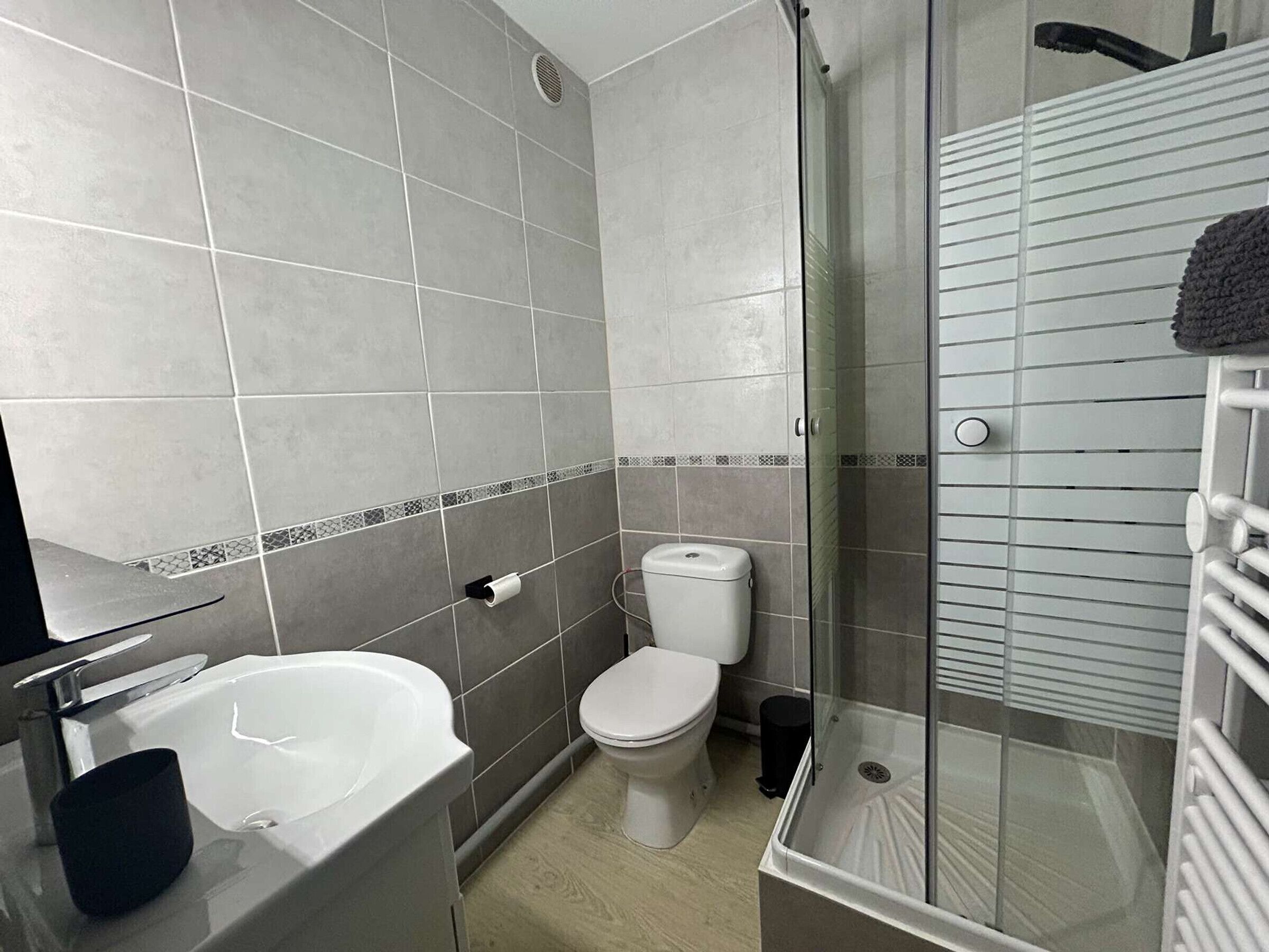 Une salle de bain équipée d’une douche, de toilettes, d’un lavabo et d’un porte-serviettes.