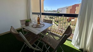 A balcony with a table, chairs, a bottle, and glasses. - Apartment port view, air conditioning - 4 guests (Cap d'Agde)