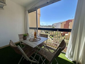 Ein Balkon mit Tisch, Stühlen, einer Flasche und Gläsern.