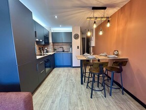 Eine moderne Küche mit dunklen Schränken, einer Holzarbeitsplatte und einem Essbereich mit Tisch und Stühlen.