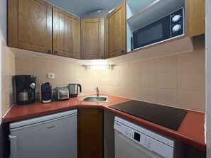 A compact kitchen with wooden cabinets, a microwave, a coffee maker, a toaster, and a dishwasher. - Comfortable apartment - 6 guests (Les Orres)
