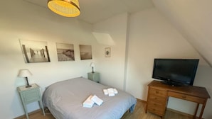 Ein Schlafzimmer mit Bett, Nachttischen, einem Fernseher und Bildern an der Wand.