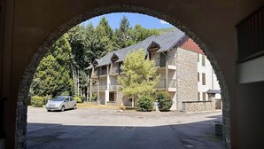 A multi-story building with a stone facade, a parking lot, and a car parked in front.