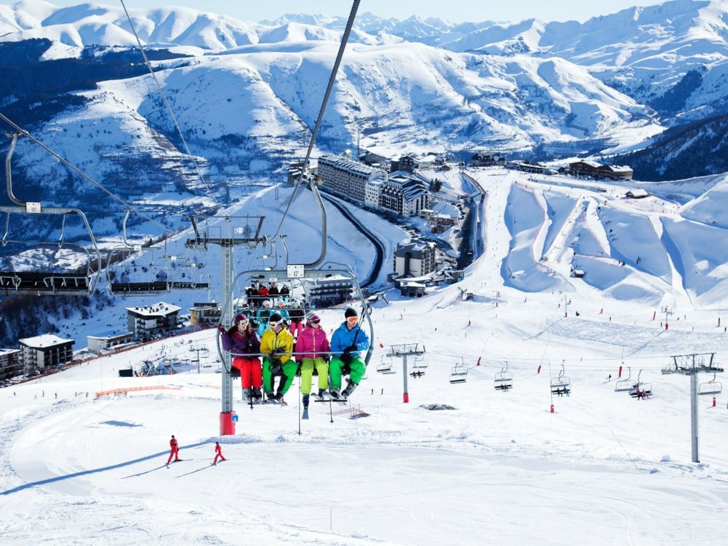 A ski lift with passengers, a snow-covered mountain landscape, and a ski resort infrastructure.