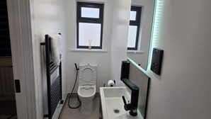 A compact bathroom with a toilet, sink, and a mirror.