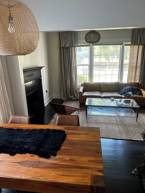 A living room with a fireplace, a sofa, a glass coffee table, and a dining table. - NEWLY remodeled 3 bedroom house in Westview Atlanta; 2.5 mi. from Stadium!! (Atlanta)
