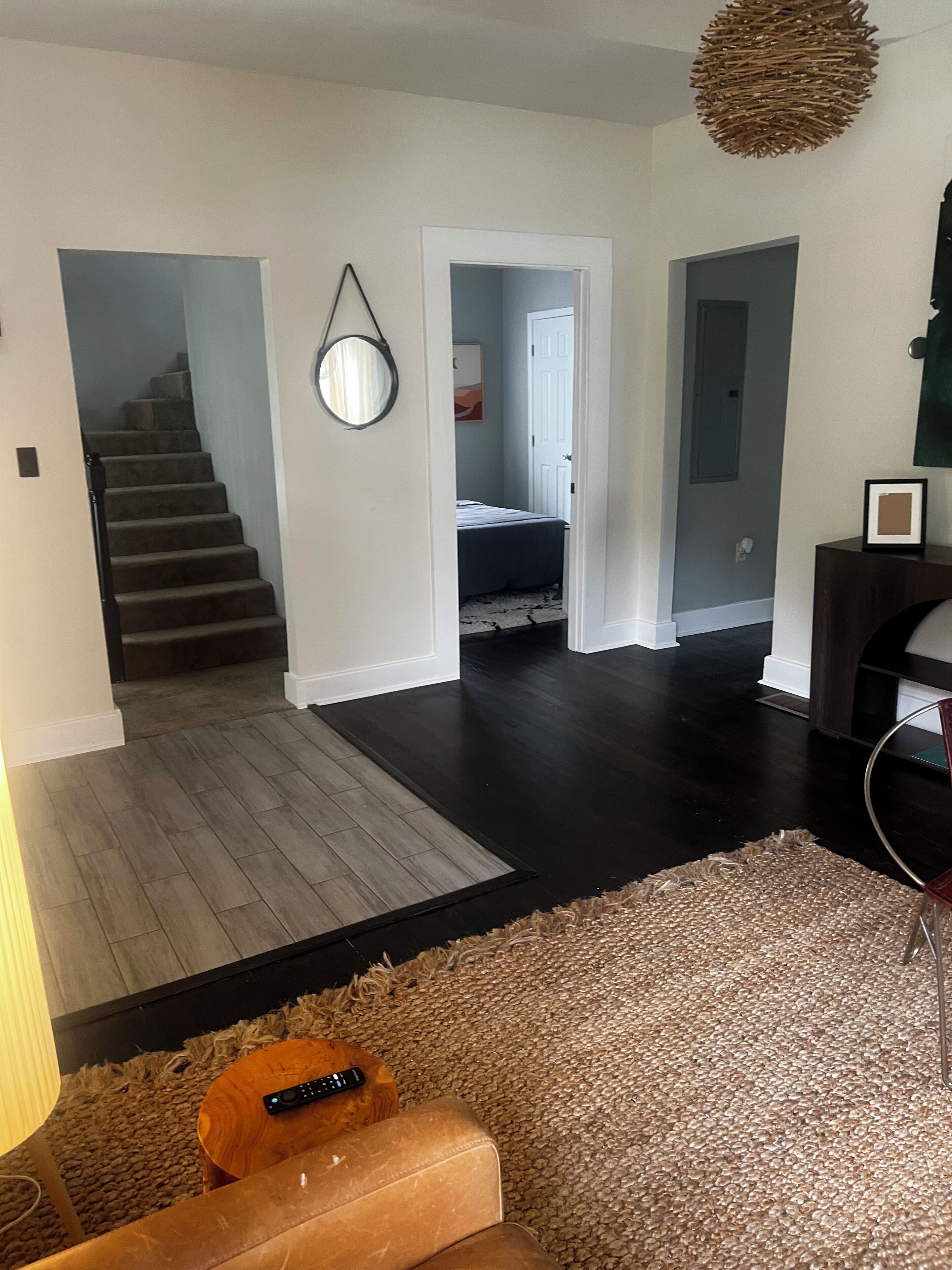 A modern living room with a staircase, a hallway, and a bedroom.