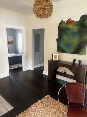 A spacious room with dark hardwood flooring, a large abstract painting, a wooden console table, and a leather chair. - NEWLY remodeled 3 bedroom house in Westview Atlanta; 2.5 mi. from Stadium!! (Atlanta)