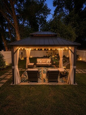 Ein Pavillon mit Lichterkette, einer Couch und zwei Stühlen.