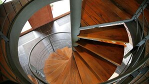 Uma escadaria em espiral com degraus de madeira e guarda-corpos de metal.