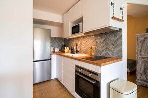 A compact kitchen with white cabinetry, a microwave, a stainless steel refrigerator, and a herringbone-patterned backsplash. - Renovated apartment with a pool, 250 meters from the beach (Sainte-Maxime)
