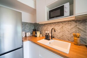 A modern kitchen with a microwave, sink, and wooden countertop. - Renovated apartment with a pool, 250 meters from the beach (Sainte-Maxime)