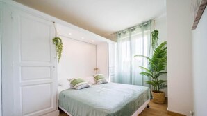 Ein Schlafzimmer mit einem Bett, einer Topfpflanze und einem Fenster mit Vorhängen.