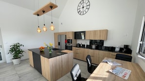 Et moderne køkken med en central ø, træskabe, indbygget ovn og en hængende lampe.