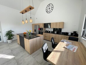 A modern kitchen with a central island, wooden cabinets, a built-in oven, and a hanging light fixture. - Ploudalmezeau House With Heated Pool (Ploudalmezeau)