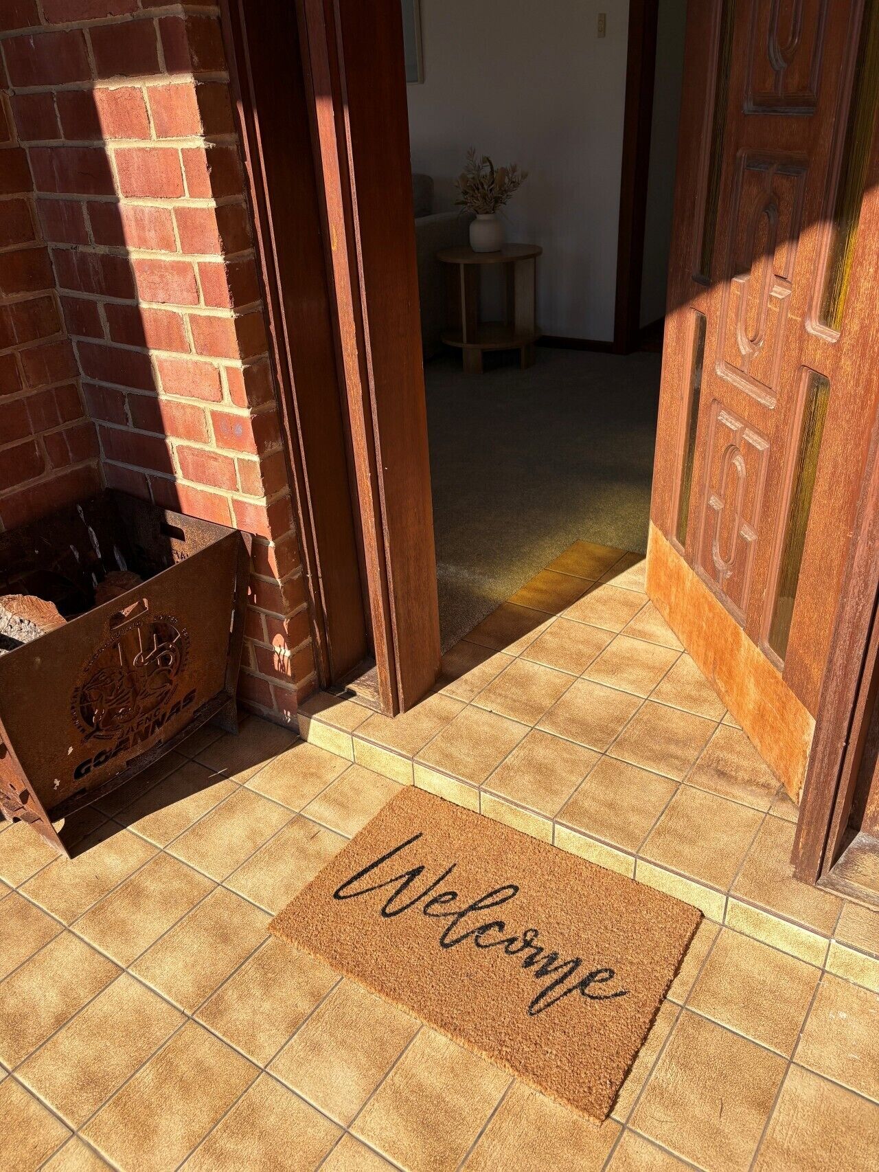 A wooden door with a welcome mat and a brick wall.