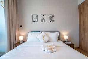 Een hotelkamer met een bed, twee nachtkastjes met lampen, een hoofdeinde en drie decoratieve wandpanelen.
