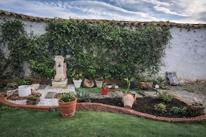 A garden with a stone fountain, potted plants, and a brick border.