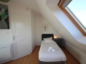 Ein Schlafzimmer mit einem Bett, einem Nachttisch mit Lampe, einer Tür und einem Fenster.