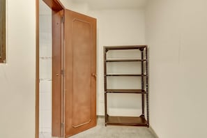 Eine Hausecke mit einer Holztür, einem Metallregal und einer gefliesten Wand.