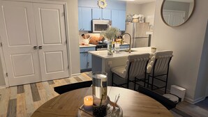 Una cocina con armarios azules, un refrigerador blanco y un comedor con una mesa redonda.