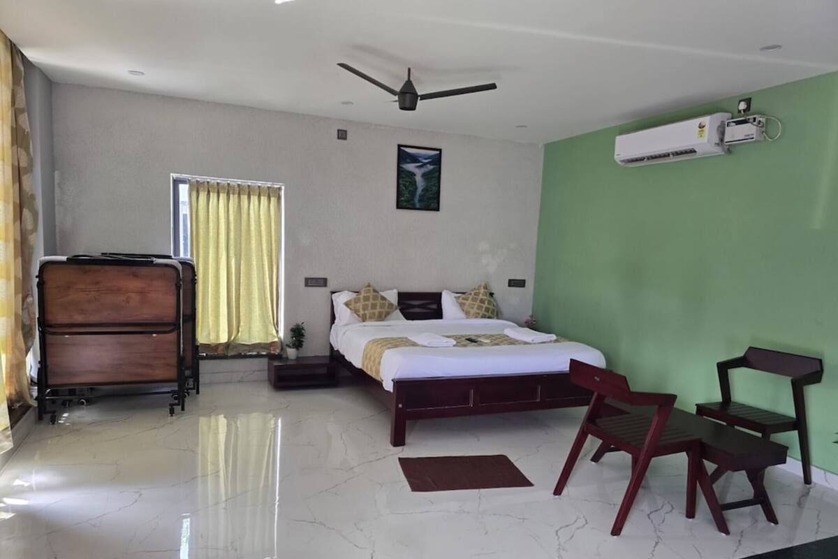 A hotel room with a bed, a desk, a chair, a ceiling fan, and an air conditioning unit.