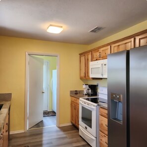 A kitchen with wooden cabinets, a stainless steel refrigerator, a microwave, and a stove.