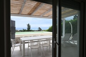 A patio with a table and chairs, a pool, and a view of the ocean. - N324 – Numana, bright one-bedroom apartment with private pool and garden (Numana)
