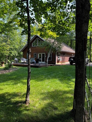A two-story wooden cabin with a porch, surrounded by a well-maintained lawn and trees. - Birch Lake-Perfect 4BR cabin on a quiet flat lot with great views in Hackensack (Hackensack)