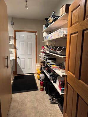 A narrow hallway with a door at the end, shelves with various items, and a black mat at the entrance. - Birch Lake-Perfect 4BR cabin on a quiet flat lot with great views in Hackensack (Hackensack)