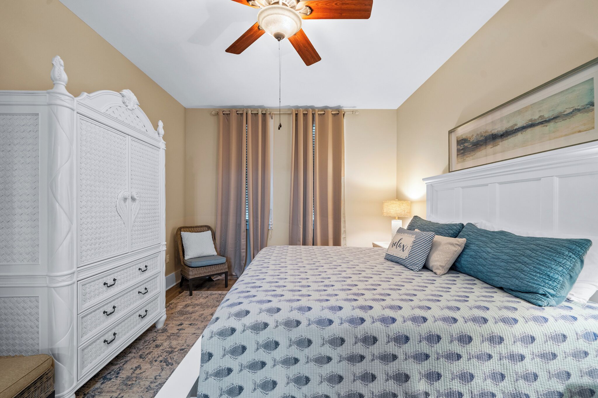A bedroom with a bed, a dresser, a chair, and a ceiling fan.