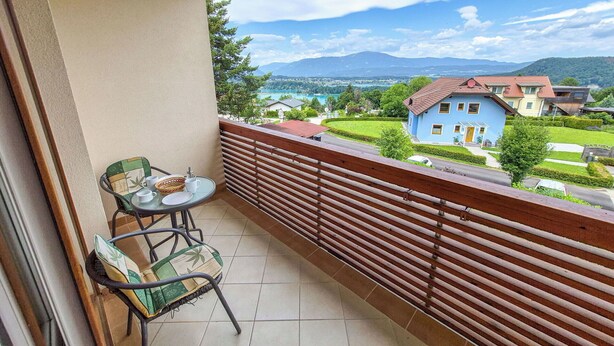 A balcony with a view of a lake, a house, and mountains. - Beautiful apartment for 3 people with WIFI, TV and balcony (Finkenstein Am Faaker See)