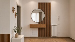 Ein modernes Badezimmer mit einem Holzwaschtisch, einem runden Spiegel, einem Blumentopf und einer Heizung.