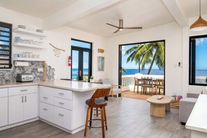 A modern kitchen with a view of the ocean, a dining area with a view, and a ceiling fan.