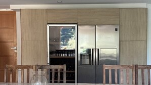 A modern kitchen with a built-in refrigerator, wooden cabinets, and a dining area with a marble table and chairs. - OLYMPE: Family Villa with a Pool on the French Riviera (L'Escarène)