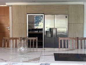 A modern kitchen with a built-in refrigerator, wooden cabinets, and a dining area with a marble table and chairs. - OLYMPE: Family Villa with a Pool on the French Riviera (L'Escarène)