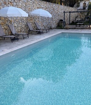 A swimming pool with lounge chairs and umbrellas, surrounded by stone walls. - OLYMPE: Family Villa with a Pool on the French Riviera (L'Escarène)