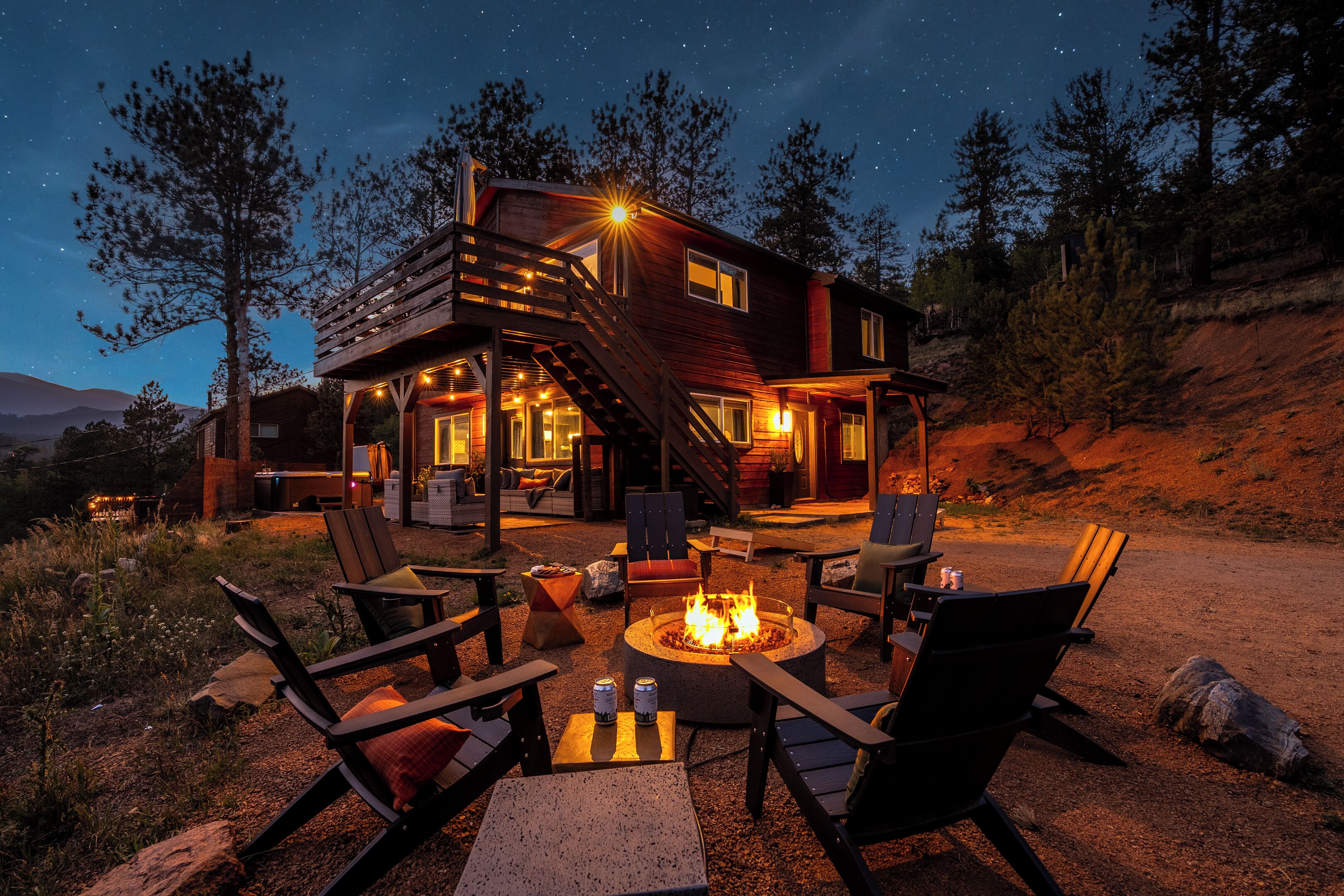 A cabin with a fire pit, outdoor seating, and a staircase leading to the upper level.