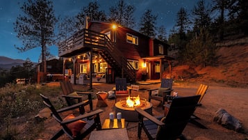 A cabin with a fire pit, outdoor seating, and a staircase leading to the upper level.