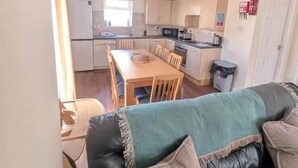 A compact living space with a kitchenette, a dining area, and a sofa with cushions. - Atlantic Reach Lodge - Spacious 4 Bedroom Retreat (Newquay)