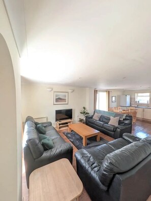 A spacious living area with a sofa set, a coffee table, and a television. - Atlantic Reach Lodge - Spacious 4 Bedroom Retreat (Newquay)