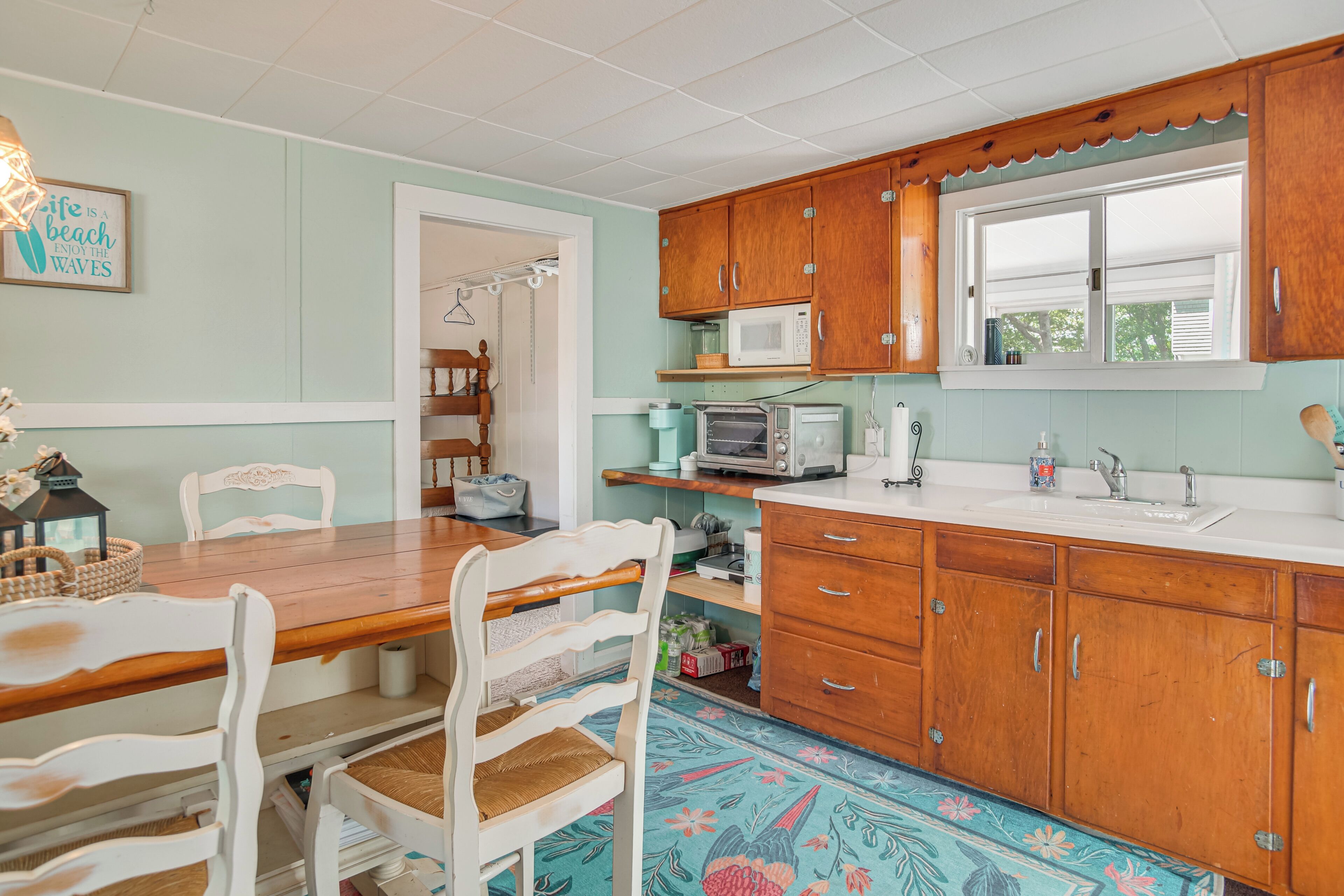A kitchen with wooden cabinets, a microwave, and a dining area with a table and chairs.