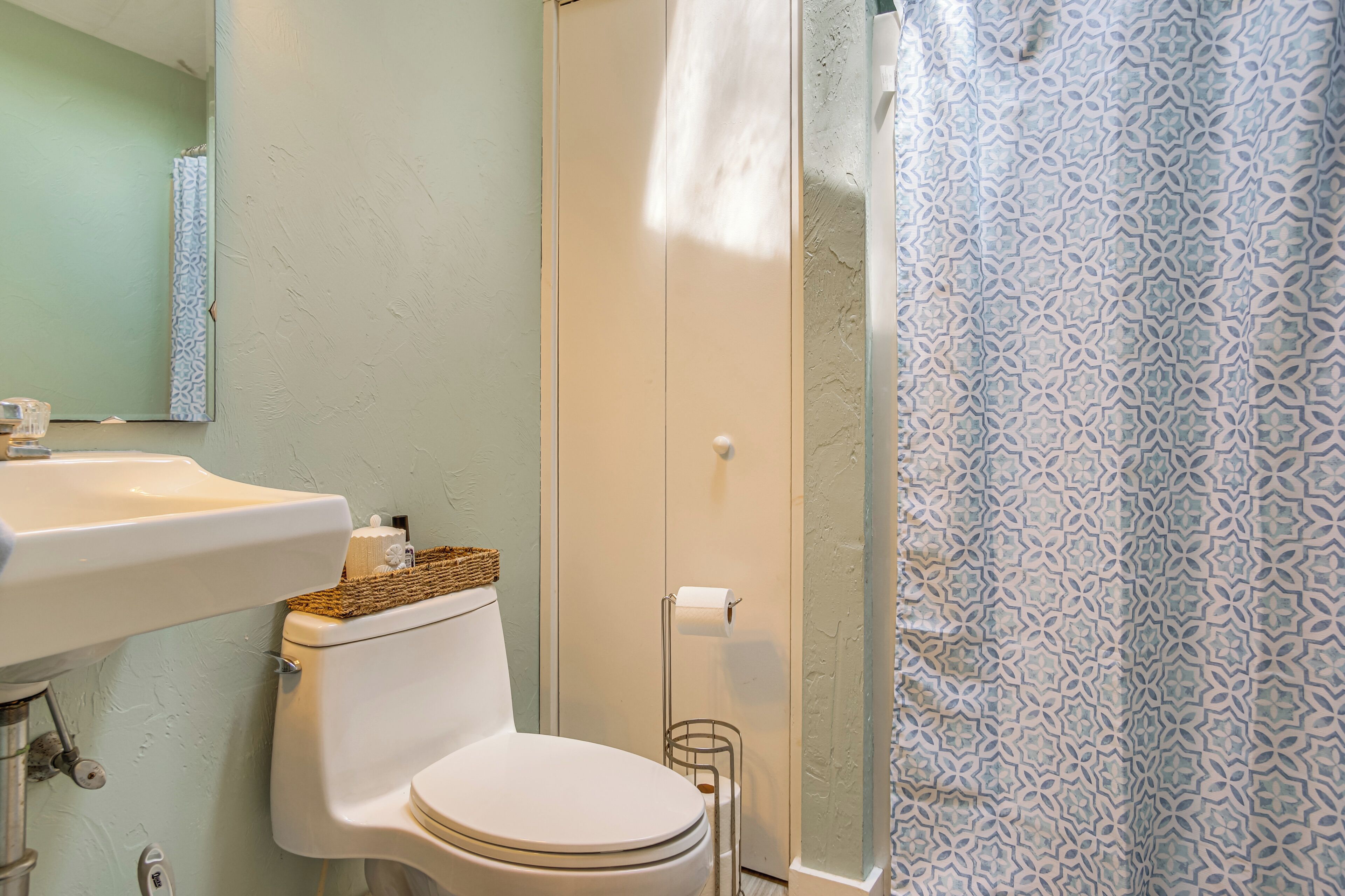 A bathroom with a toilet, sink, and shower curtain.