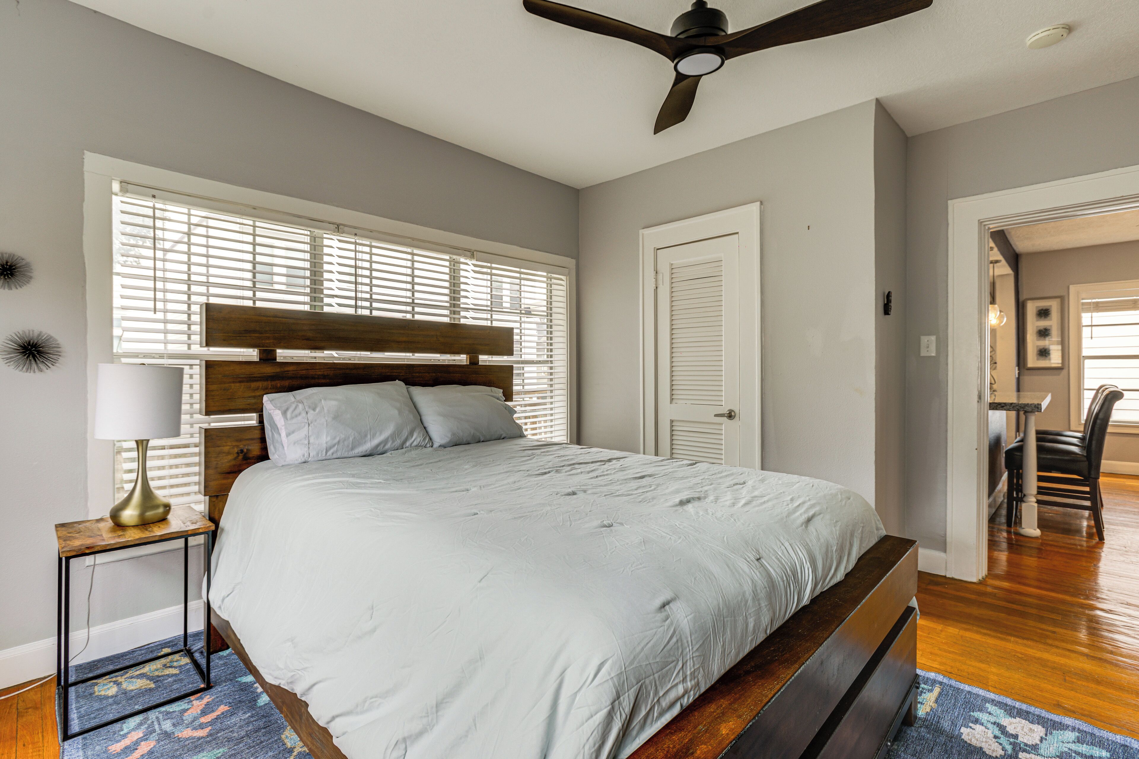 A bedroom with a bed, a ceiling fan, a nightstand, and a window with blinds.