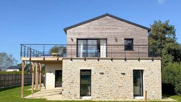 A modern two-story house with a stone facade, large windows, and a balcony.
