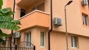 A multi-story building with balconies, air conditioning units, and a gated entrance. - Sea View Apartment with Terrace & Garden in the Heart of Tsarevo (Tsarevo)