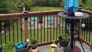Una terraza con mesa, sillas, un paraguas azul y plantas en macetas.
