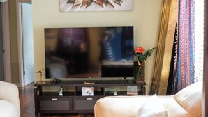 Ein Wohnzimmer mit Flachbildfernseher, einer Couch, einem Couchtisch und einem Wanddekor.